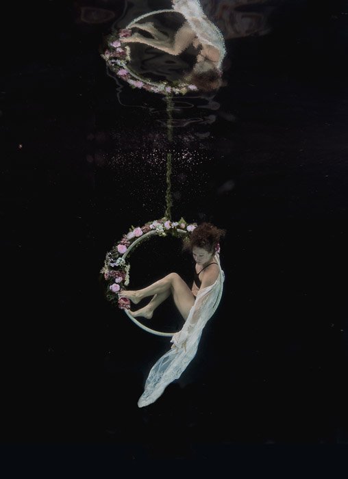 Красивая и атмосферная фотография девушки, позирующей под водой на обруче