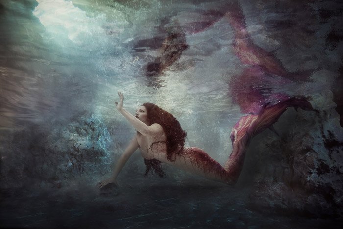 Красивая и мистическая подводная фотография девушки-русалки, плавающей под водой
