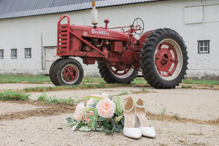 Свадебная фотография натюрморт пары свадебных туфель и букета на фоне красного трактора