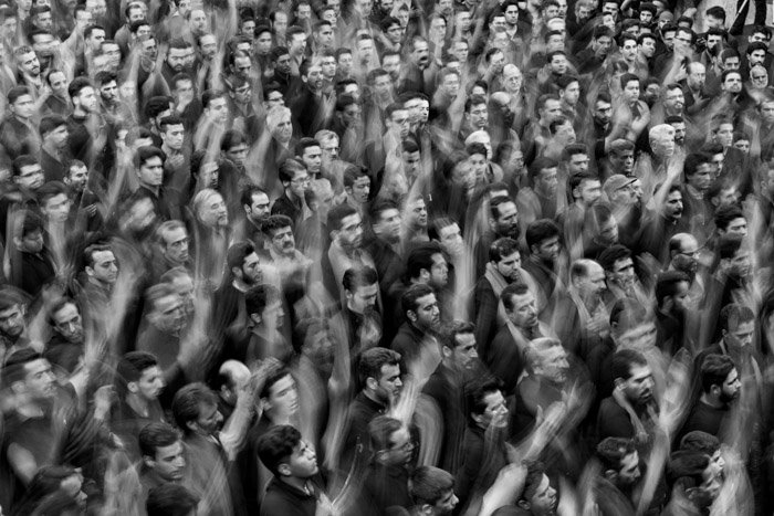 Черно-белая фотография толпы людей с поднятыми вверх руками