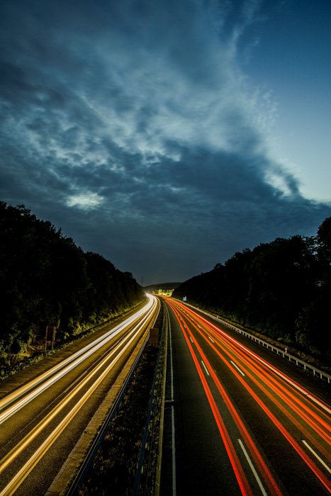 Вид с воздуха на шоссе ночью с цветными потоками световых следов от автомобилей 