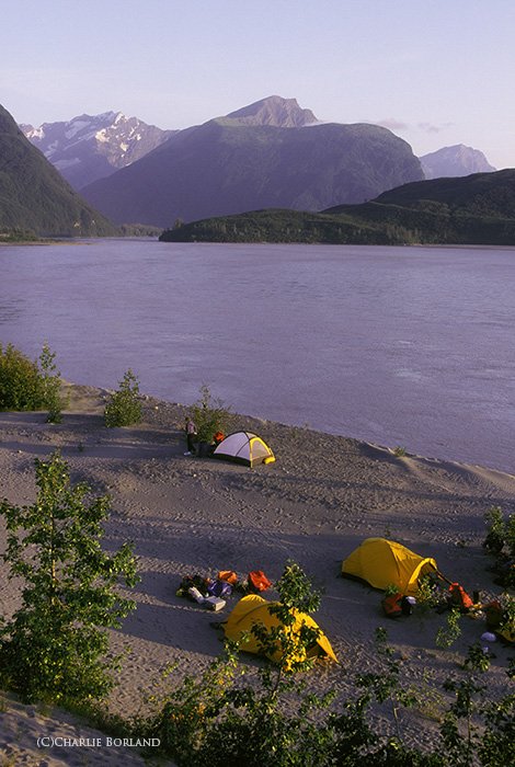 вид на палатки у озера с горами на горизонте