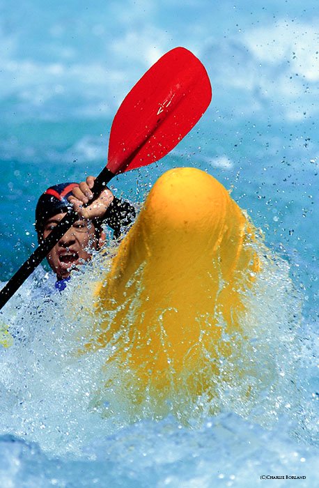 close up of person rowing the rapids in yellow boat with red oar in bright crystal blue waters