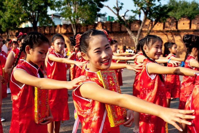 Азиатские девушки в традиционных красных платьях выстраиваются на параде в честь китайского нового года в Чиангмае, Таиланд.