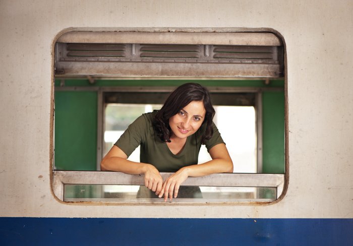 Привлекательная молодая женщина смотрит в окно старого поезда, демонстрируя центральное композиционное обрамление.