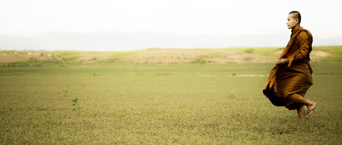 яркий и воздушный кинематографический фотопортрет монаха на зеленом поле