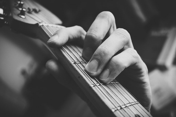 Черно-белая фотография руки человека, играющего на гитаре, крупным планом
