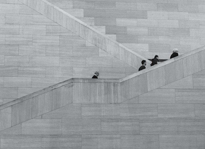 Черно-белая фотография четырех человек, поднимающихся по каменной лестнице