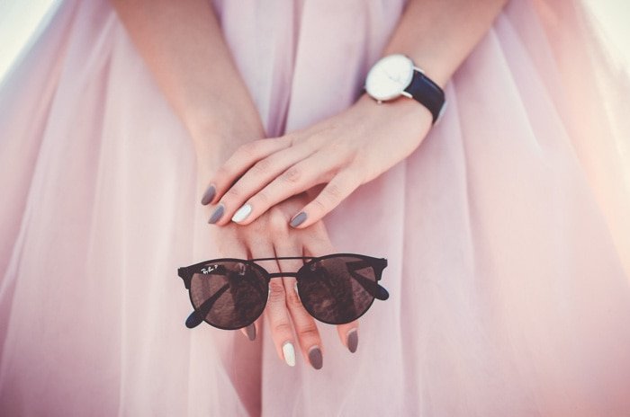 крупный план модели в розовом платье, держащей солнцезащитные очки
