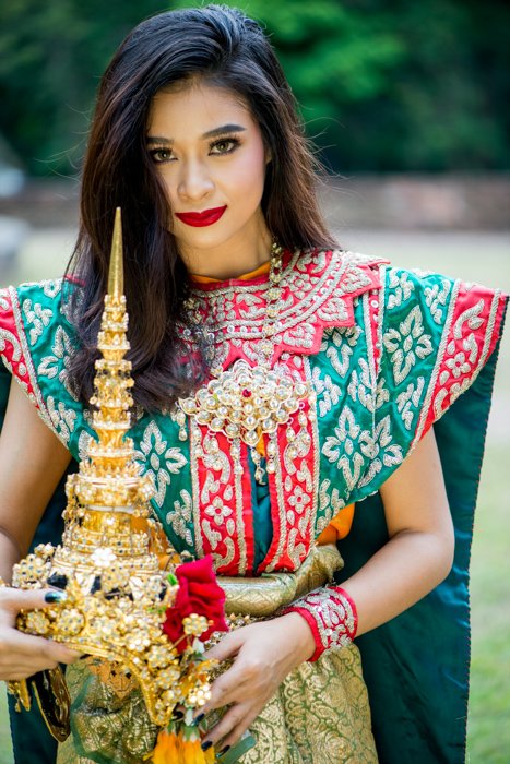 Красивая женщина-модель в классическом тайском костюме держит реквизит для фотографии для дополнительного эффекта