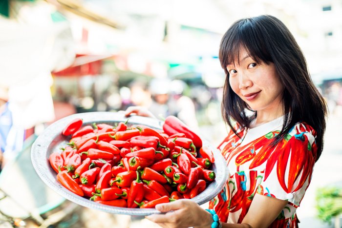 Молодая симпатичная азиатка на открытом рынке с перцем чили. - photography props