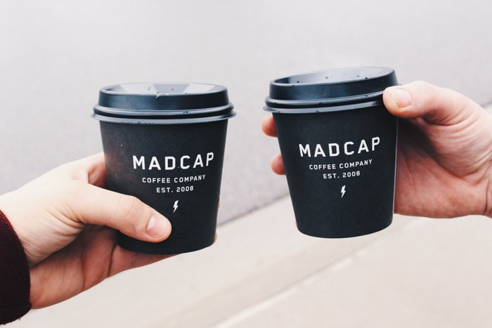две руки держат черные стаканчики с кофе на вынос