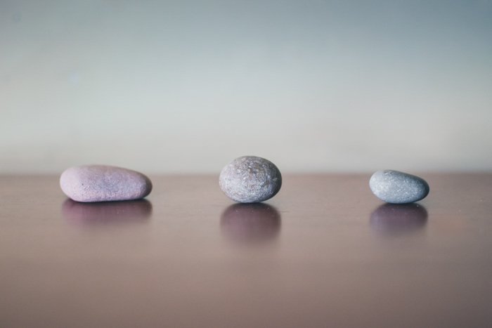 три серых камня на деревянной поверхности