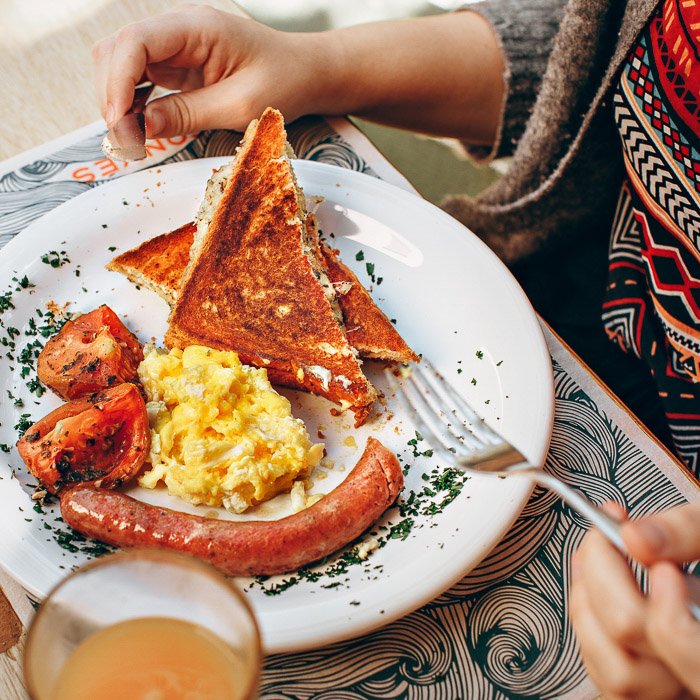 Фуд-фотография смартфона, на которой за столом человек ест аппетитно выглядящий поздний завтрак