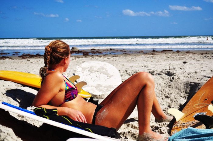 женщина в бикини лежит на пляже и смотрит на синее море