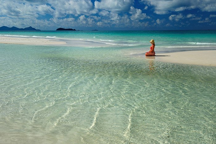Женщина, сидящая на берегу красивого пляжа, снятая с использованием верхнего освещения