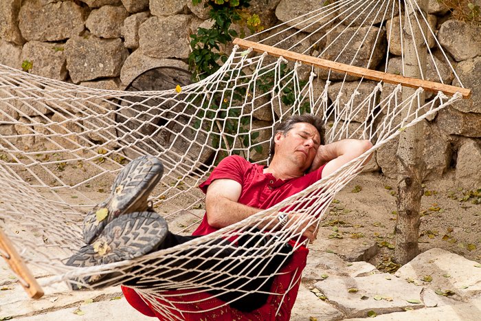 мужчина в красной рубашке спит в гамаке на открытом воздухе, каменная стена на заднем плане - советы по безопасности путешествий для фотографов