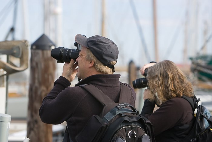Мужчина и женщина на пирсе с зеркальными фотоаппаратами фотографируют
