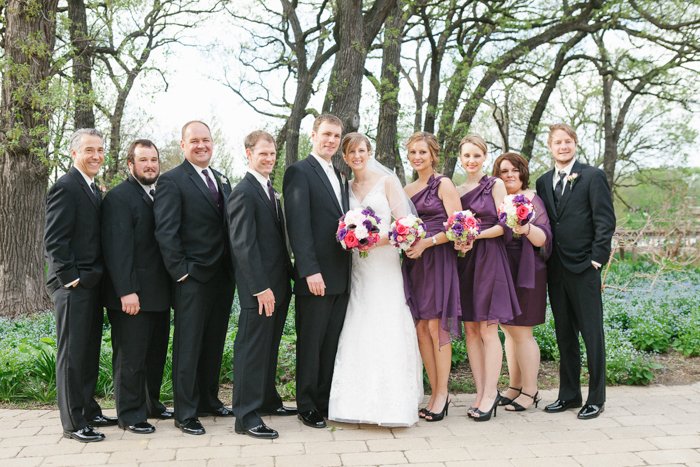 Свадебный антураж с женихами и подружками невесты в фиолетовом на открытом воздухе на фоне редких весенних деревьев