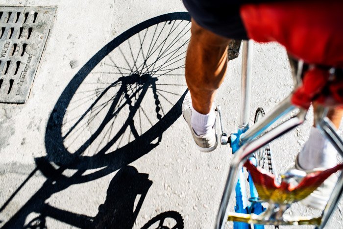 Крупный план велосипедиста, крутящего педали, с тенями, отбрасываемыми на каменную землю, лучшее время суток для фотографий