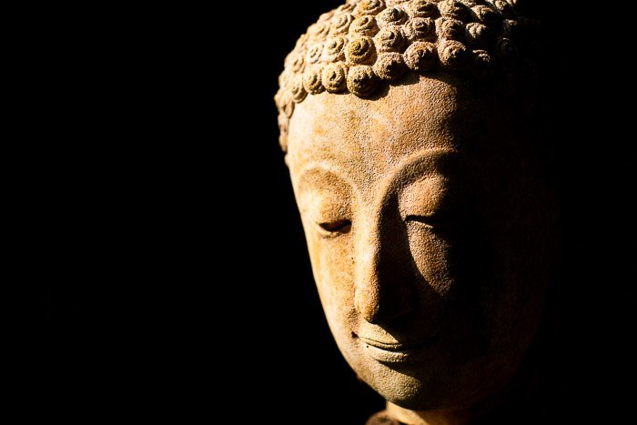 Атмосферная фотография каменного Будды, сделанная на открытом воздухе при естественном освещении