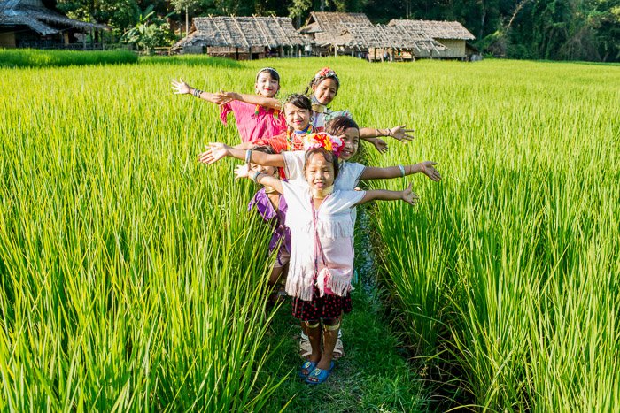Фотоснимок группы детей, позирующих на рисовом поле в естественном свете - лучшее время для съемки на открытом воздухе