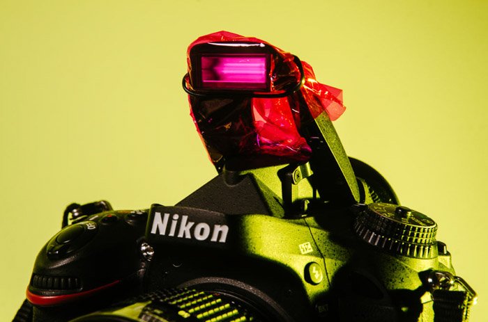 Крупный план камеры Nikon с розовым целлофаном, закрывающим вспышку - цветная гелевая фотография