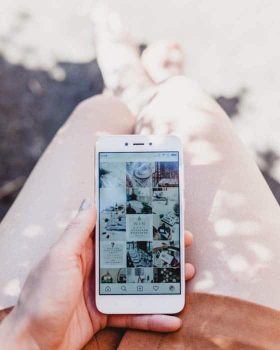 Человек держит смартфон и загружает фотографии в Instagram 