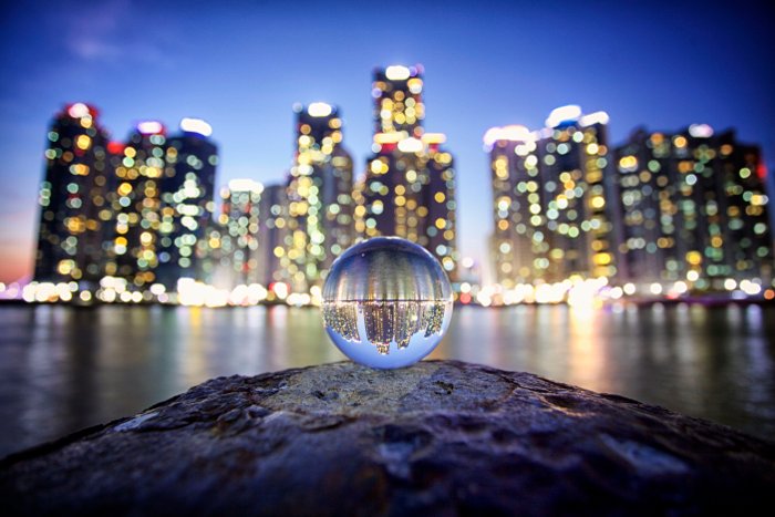 Потрясающий снимок городского пейзажа, сделанный через хрустальный шар, демонстрирующий красивый преломленный свет