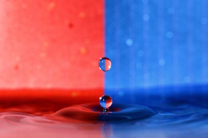 Фотография капли воды с использованием преломленного света на синем и красном фоне