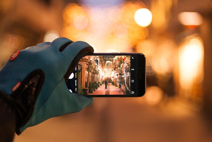 Человек, фотографирующий смартфоном рождественские огни на улице