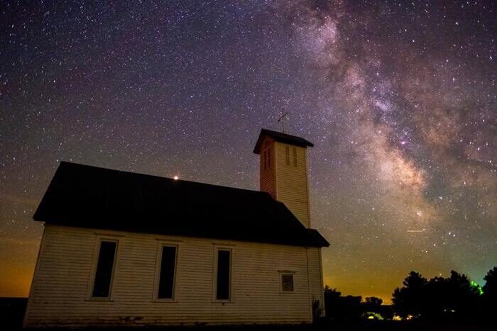 Фотография небольшой церкви с млечным путем на ночном небе