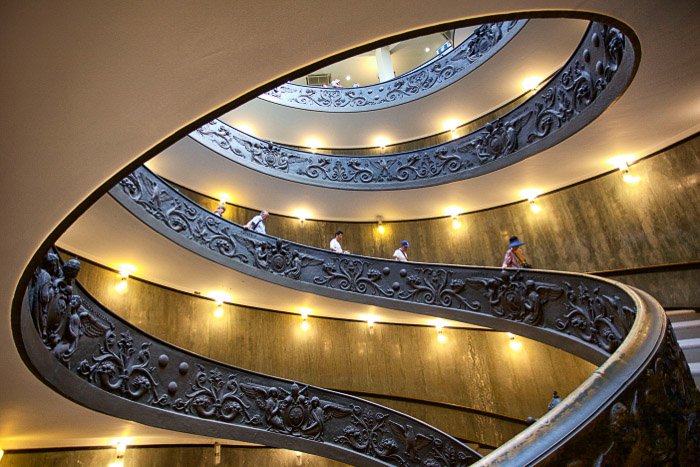 Люди идут по винтовой лестнице в интерьере впечатляющего здания