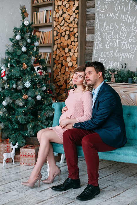 Рождественское фото пары, позирующей на диване у елки
