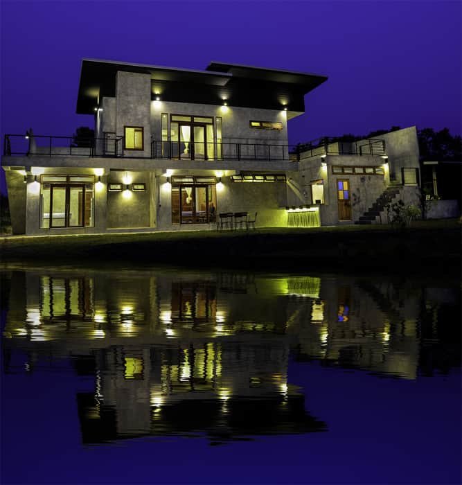 Строгий архитектурный снимок дома в сумерках с крутым фотошопным отражением в воде внизу