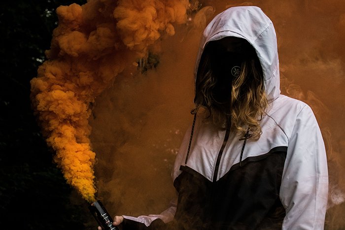 Безликий портрет женщины, держащей оранжевые дымовые гранаты