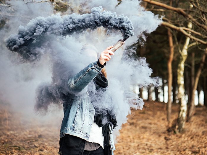Asmoke bomb photography portrait of the woman holding blue smoke grenade near his face