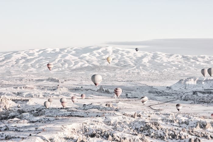 Много воздушных шаров в полете над снежным пейзажем