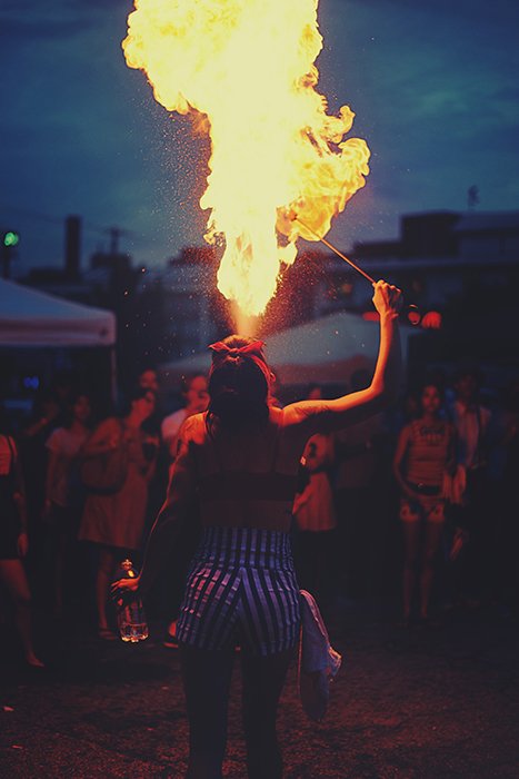 Огненный танцор, выдыхающий пламя во время ночного фестиваля