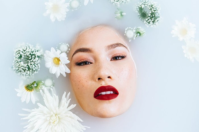 Красивая фотография молочной ванны женской модели в окружении белых цветов