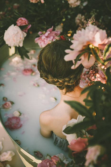 Красивая фотография молочной ванны женской модели в окружении цветов