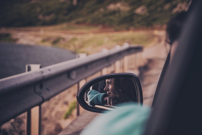 отражение молодой женщины в боковом зеркале автомобиля