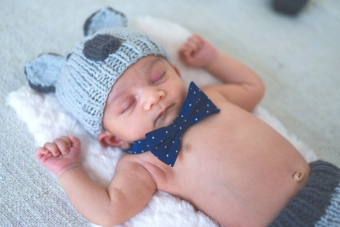Новорожденный с голой грудью в забавной шапочке и дикки-бабочке как реквизит для фотографии новорожденных