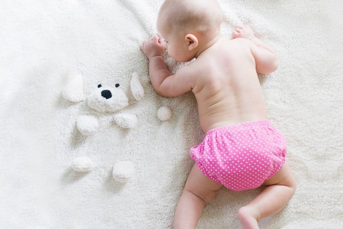 Новорожденный ребенок позирует на плюшевом коврике