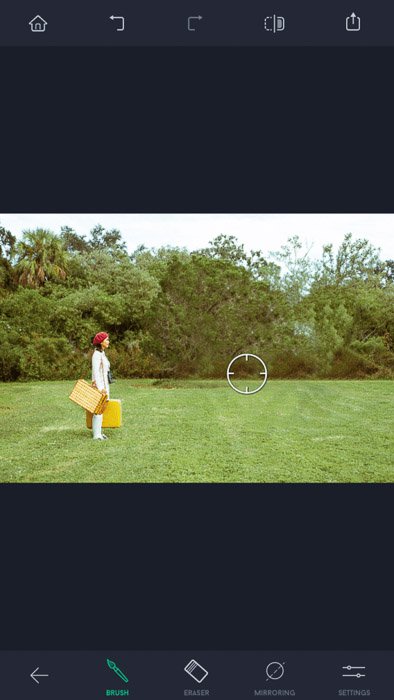 Скриншот приложения для сенсорной ретуши, женщина в красной шляпе и с желтыми сумками стоит на поле, виден инструмент 