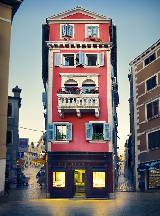Причудливое красное здание выделяется своей симметрией, яркими цветами и теплым светом
