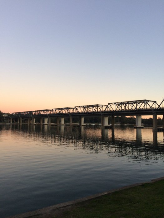 силуэт длинного моста над водой на закате