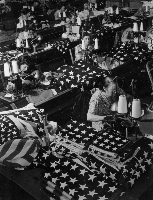 Черно-белый снимок женщин, шьющих американские флаги, сделанный военным фотографом Маргарет Борк-Уайт