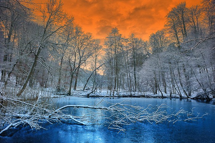 Озеро в окружении ледяных деревьев и потрясающего оранжевого неба - фото драматического неба