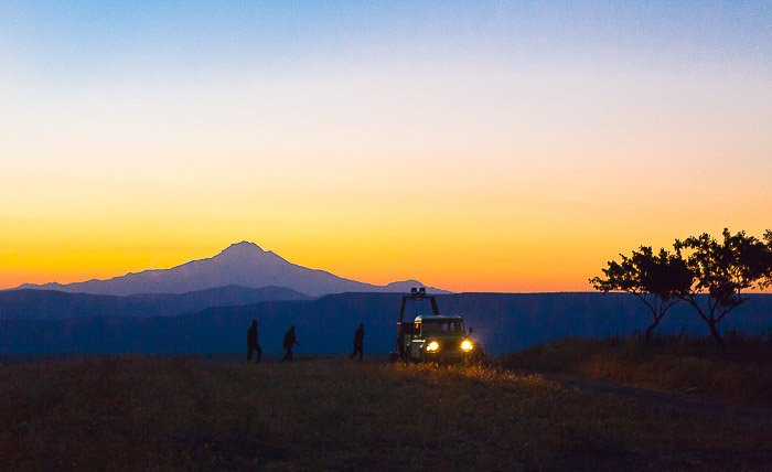 Вечерний пейзаж гор с силуэтами фотографов, готовящихся к съемке на воздушном шаре
